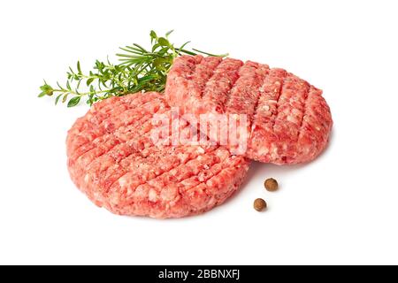 Two raw burger patties with thyme and reosemary on white Stock Photo
