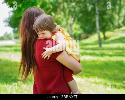 Mother holding her crying one-year old baby girl with tears close up Stock Photo
