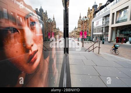 Glasgow, Scotland, UK. 1 April, 2020. Effects of Coronavirus lockdown on streets of Glasgow, Scotland. Photo of model in Victoria's Secret shop looks out on a deserted Buchanan Street with a lone Deliveroo cyclist riding past .Iain Masterton/Alamy Live News