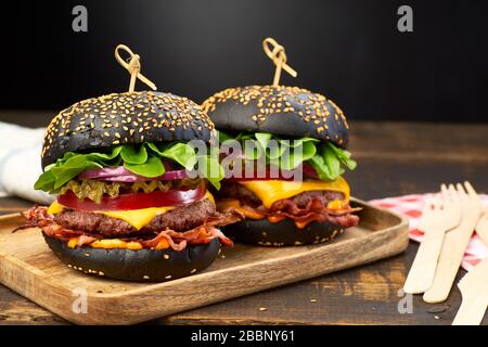 Two huge black hamburgers on dark wooden background Stock Photo