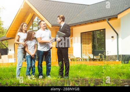 real estate agent is selling an apartment to a young family. conclusion of a lease and purchase of a house, apartment. man shows housing Stock Photo