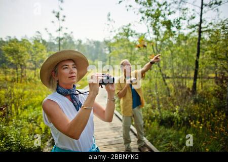 Happy mature couple birdwatching in woodland. Stock Photo