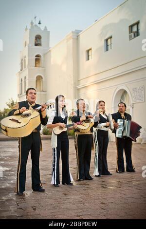 Group of musicians in matching costume playing in a courtyard outside a church. Stock Photo