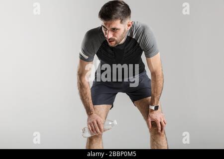 Image of young tired man in sportswear resting while working out isolated over gray background Stock Photo