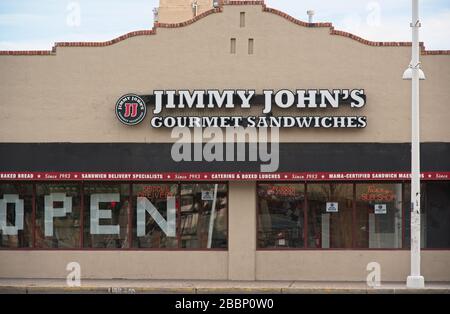 Jimmy John's Sandwiches on Central Ave. In Albuquerque near the University of Noe Mexico.  Neon sign in the window says 'Serious Delivery', which tie. Stock Photo