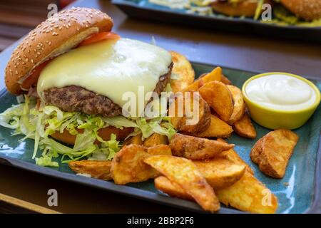 Grilled cheeseburger with potato chips and mayonese Stock Photo