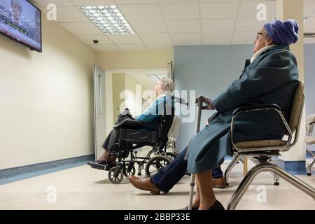 Elderly women watching TV in outpatient clinic waiting room in NHS hospital. UK Stock Photo