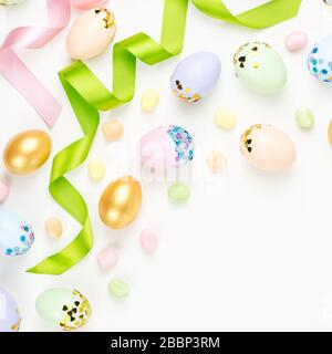 Festive Easter background with decorated eggs, flowers, candy and ribbons in pastel colors on white background Stock Photo