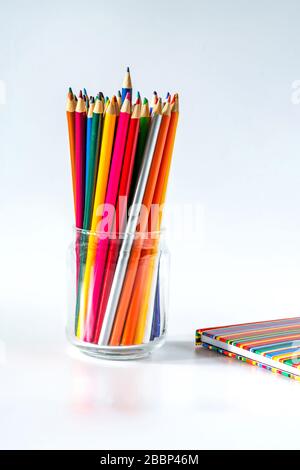 Colorful pencils and a notebook on white background Stock Photo