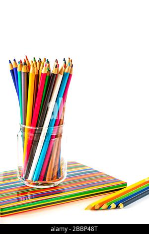 Colorful pencils and a notebook on white background Stock Photo