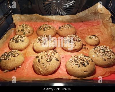 Roll , bun or bread in hot stove which get backen - crispy with grains ( pumkin seed & sunflower pit ) - fast breakfast - self-made - convenience food Stock Photo