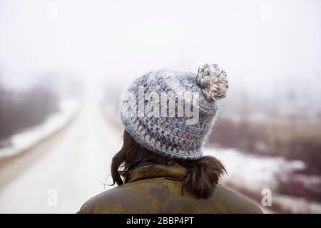 A lady walks alone on a gravel road during the emergency regulations regarding the coronavirus / COVID-19, on a foggy cold spring day. Stock Photo