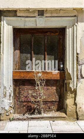 Door of abandoned, dilapidated house and weeds growing in front of the door Stock Photo