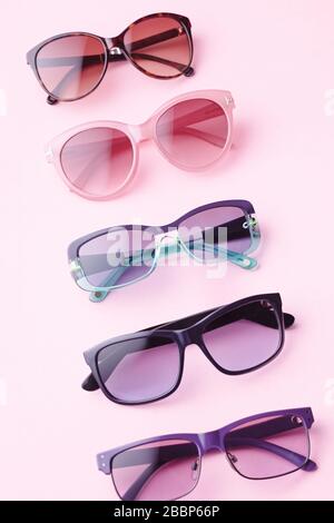 Collection of fashionable sunglasses on pink background. Sunglasses of different shapes and colors flat lay. Oval shaped sunglasses, oversized, wayfar Stock Photo