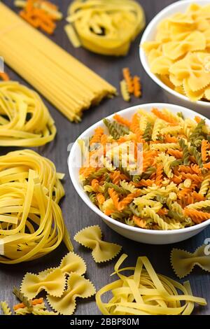 Italian food ingredients with various pasta, vegetables, mushrooms, olives. Flat lay on dark wooden background. Mediterranean cuisine concept Stock Photo