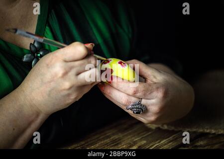Holidays, traditional concept - close up of woman hands coloring Easter eggs with brush. Preparation for Easter. Close-up. Horizontal orientation. Cop Stock Photo