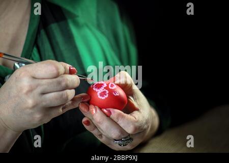 Woman painting Easter eggs on wooden background. Decorating egg. Preparation for Easter. Close-up. Horizontal orientation. Copy space. Stock Photo