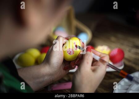 Happy easter! Female hands painting eggs with floral patterns. Preparing for Easter. Artist paints an Easter egg. Close-up. Selective focus. Stock Photo