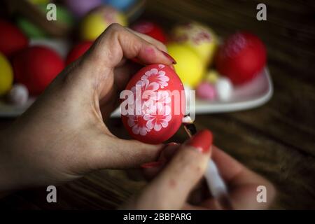Close-up of woman's hands painting an easter egg. Painting Easter eggs. Painting eggs for easter holiday celebration. Happy easter. Low Key. Stock Photo