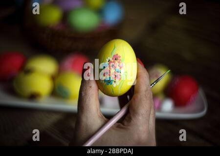 Woman hands is holding eggs with floral patterns. Preparing for Easter. Artist paints an Easter egg. Close-up. Selective focus. Copy space. Horizontal Stock Photo