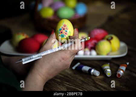 Woman hands is holding eggs with floral patterns. Preparing for Easter. Artist paints an Easter egg. Close-up. Selective focus. Copy space. Horizontal Stock Photo