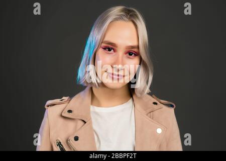 Beautiful trendy woman with blonde hair on grey studio background. Hipster girl portrait. Fashion, style, freedom, youth concept. Stock Photo