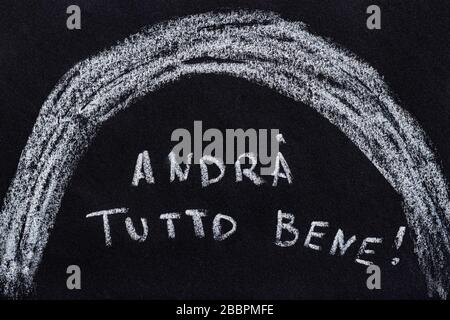 Drawing with chalk on a black blackboard, handwritten italian text andrá tutto bene which translate as everything will be fine Stock Photo