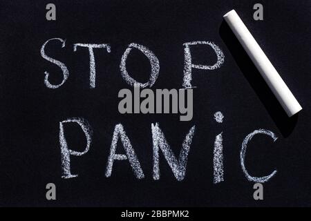 Drawing with chalk on a black blackboard, handwritten text Stop Panic. Stock Photo