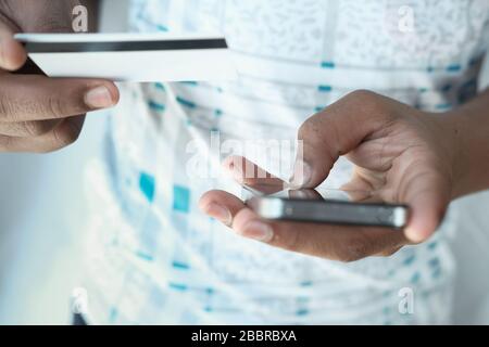 Man's hands holding a credit card using smart phone for online shopping Stock Photo