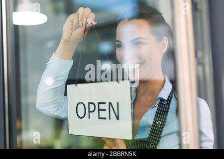 Woman holding open sign in cafe Stock Photo