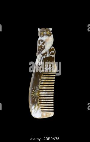 Natural horn engraved comb owl pattern isolated on black background. Stock Photo