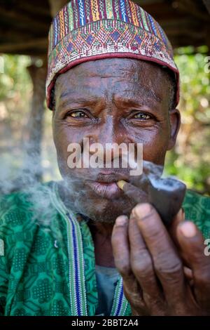 Portrait of a Fulani man with facial tattoos smoking a pipe. Stock Photo