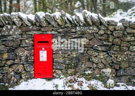 A bright ref GR letterbox mounted into a stone wall near Loughrigg Tarn in the English Lake District National Park Stock Photo