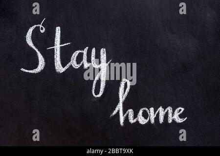 Drawing with chalk on a black blackboard with text Stay Home. Concept of virus protection Stock Photo