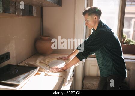 Man potter looking for ware for a work. Young man potter in his workshop. Handsome man work Stock Photo