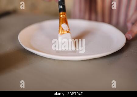 Close up of potter's hands making ornament on ceramic product. Plate in male's hands. Young artist Stock Photo