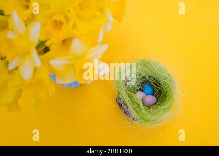 Easter holiday decorations on yellow background. Colorful easter painted speckled eggs in basket. Creative spring composition with Easter elements - f Stock Photo