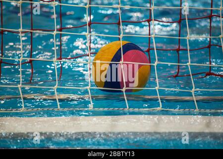 Water polo ball floating on blue swimming pool water Stock Photo