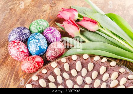 colorful easter eggs, easter cake and tulips on wooden table Stock Photo