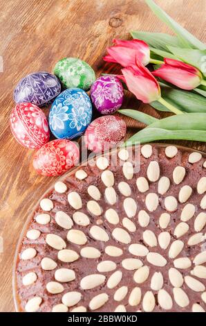 colorful easter eggs, easter cake and tulips on wooden table Stock Photo