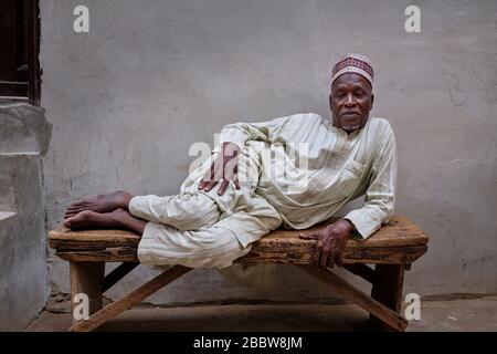 Portrait of a middle aged Nigerian man lying on a wooden bench. Stock Photo