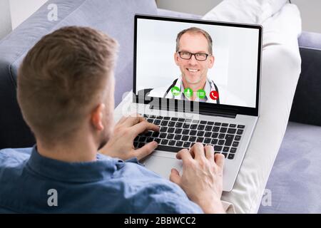 Close-up Of A Man Videoconferencing With Happy Doctor On Laptop Stock Photo