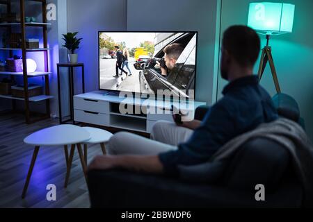 Man Lying On Sofa Watching Television At Home Stock Photo