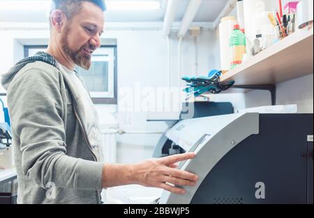 Man working on large format printer in advertising material agency Stock Photo