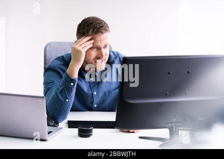 Stressed Young Businessman Sitting At Desk In Office Stock Photo