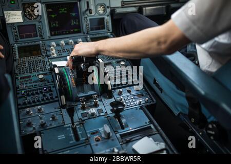 Pilot's hand accelerating on the throttle in  a commercial airliner airplane flight cockpit during takeoff Stock Photo