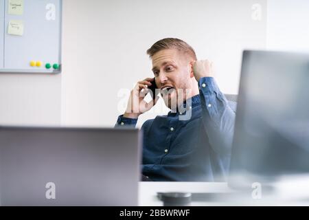 Smiling Businessman Looking Away While Communicating On Mobile Phone In Office Stock Photo