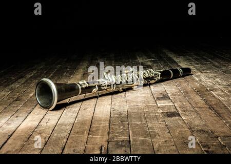 black woodwind clarinet lies on a brown wooden stage Stock Photo