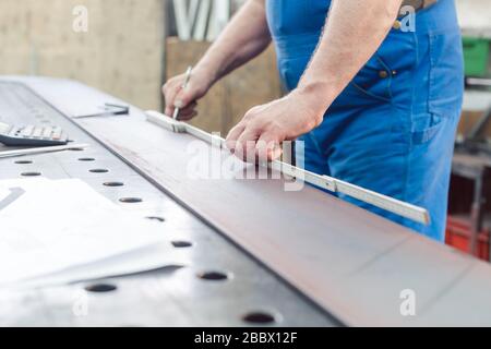 Metalworker using folding rule to measure steel strip Stock Photo