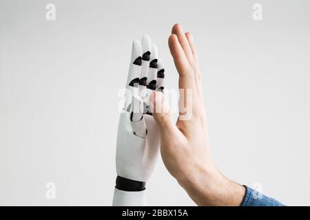 Close-up Of Robot And Man Giving High Five Against Gray Background Stock Photo